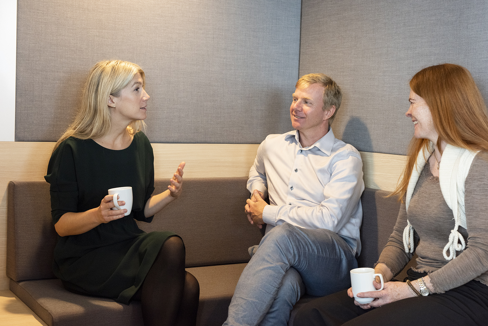 Tre kolleger i sittegruppe p&aring; kontoret